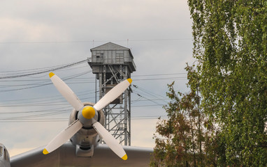 Wing of an airplane with a propeller on a background of a gray tower