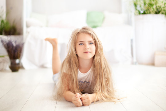 Childhood concept. The child plays in the children's room. Little blonde girl in pajamas at home. time for sleep and rest. Baby girl in a cozy Scandinavian bedroom. The child lies on the floor at home
