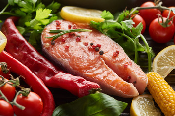 raw salmon steak with spices, vegetables and greenery