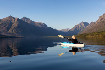 Adventurous Man Kayaking in Lake McDonald during a sunny summer evening with American Rocky...