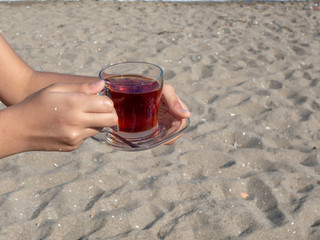 lady holding a cup of tea on the beach