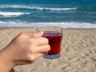 lady holding a cup of tea on the beach