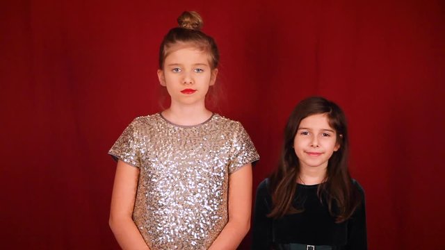 Two girls, one, mean and annoyed, the other with a smirky grin. Mean girl looks angry. They both seem tired, mean girl yawns and hits sister.