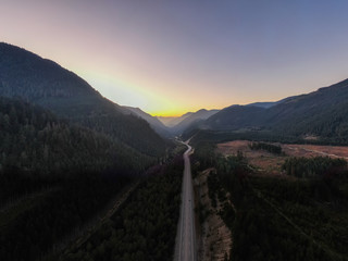 Aerial View of a Scenic Road in the Valley surrounded by Canadian Mountain Landscape during a sunny summer sunset. Taken near Hope, East of Vancouver, BC, Canada.
