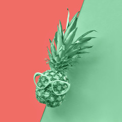 Funny pineapple in heart-shaped glasses on split paper background in neo green and salmon colors