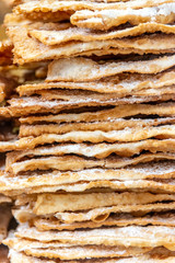 Closeup of Angel Wings, a traditional sweet crisp pastry made out of dough shaped into thin twisted ribbons, deep-fried and sprinkled with powdered sugar, that originated in Ancient Roman cuisine