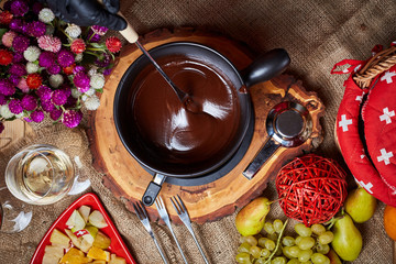 Composition with chocolate fondue in pot and space for text on marble background