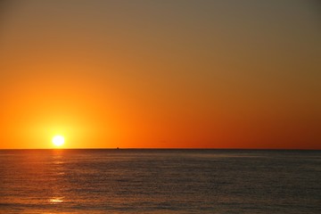 Fototapeta na wymiar Beautiful Orange Sunrise over the Atlantic Ocean Creating Glowing Ripples on the Blue Water in Florida in a Clear Dry Morning in April