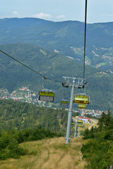 Chairlift in the Silesian Beskids mountains with Szczyrk town in the distance and forest in the background