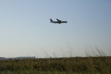 the plane flies over the field at sunset. Passenger air transport.