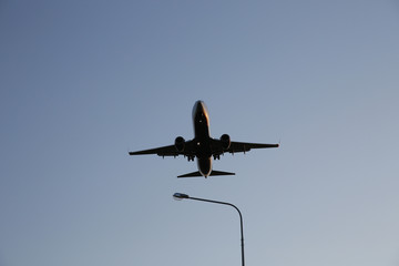Airplane flies low over a city lighting lantern. The plane is landing. Air passenger transport.