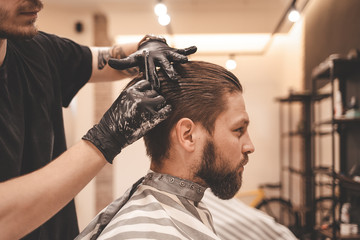 hairdresser combing hair with a comb in barbershop