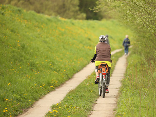Obraz premium An old gray-haired woman rides a bicycle among the greens. A healthy and active part of life. Ecological transport for the population. Free time for retirement. Movement in space. Sports for the elder
