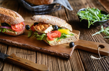 Wholemeal vegetarian baguette stuffed with grilled white cheese, arugula, tomatoes, black olives, bell pepper and red onion