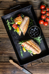 Fototapeta na wymiar Wholemeal vegetarian baguette stuffed with grilled white cheese, arugula, tomatoes, black olives, bell pepper and red onion