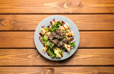 Salad with cheese, meat and herbs on a wooden background
