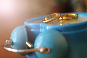 wedding ring and alarm clock on wood