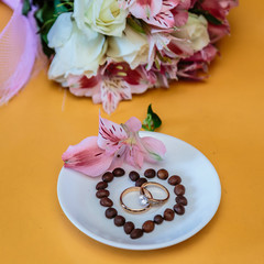 Fototapeta na wymiar Coffee, flowers and wedding rings. Close-up.