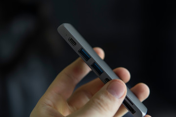 Man's hand holding The USB adapter under the Type-C connector for laptop. Multiport station for laptop with multiple different ports. USB to USB Type-C Hub Converter.