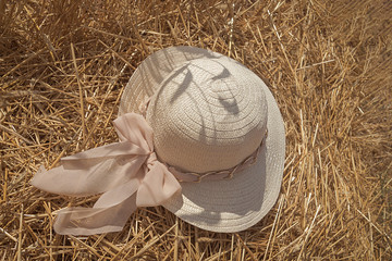 Sombrero de paja con un lazo rosa colocado en un campo de trigo recientemente recogido  con 