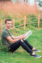 Happy young urban man with book outdoors