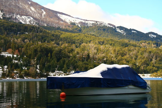 barco tapado con nieve arriba, flotando en un lago