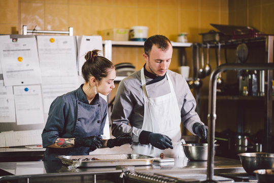 Cheerful Experienced Man And Woman Staff. Profession preparation confectionery products. Caucasian man and woman two employees colleague teamwork pastry chef. Theme cooking chocolates truffle