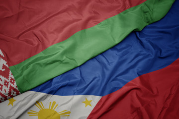 waving colorful flag of philippines and national flag of belarus.