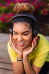 Pretty young black african american woman listening to music with a headphone outdoor