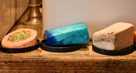 An image of three various decorative soap bars of different colors (pink, green, blue and white) and shapes (round and rectangular) made of natural ingredients