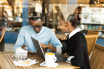 Black  African American coworkers doing digital teamwork arround a coffee cup