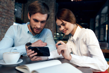 man and woman working on tablet computer in cafe