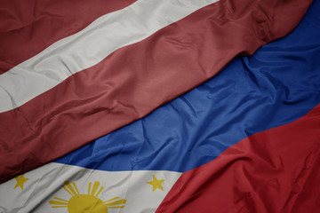 waving colorful flag of philippines and national flag of latvia.