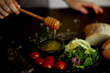 Tasty and healthy food. Black background, handmade pottery.Hand raises a spoon for honey. Honey flows down. Beautiful color