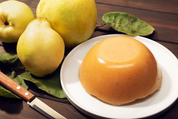 Homemade quince jelly and fruits on wooden background