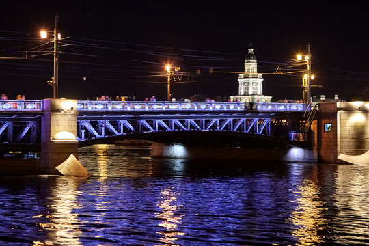 Palace Bridge across the Neva River. Cityscape with Kunstkamera building. Night city lights, ripples, colorful reflection in water. Saint Petersburg, Russia