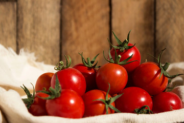 Ripe red cherry tomatoes on a white cloth, and on a wooden background. Useful vegetables.