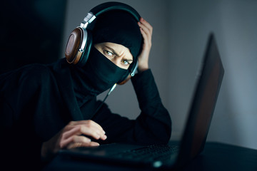 thief in balaclava with laptop
