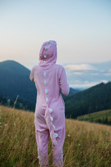 Young woman in pink dragon costume standing on a mountain top. Calm and inspiration on high peak of mountain