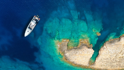 Aerial top view luxury inflatable rib speed boat docked in mediterranean emerald rocky bay with crystal clear sea