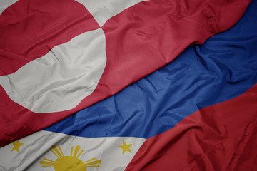 waving colorful flag of philippines and national flag of greenland.