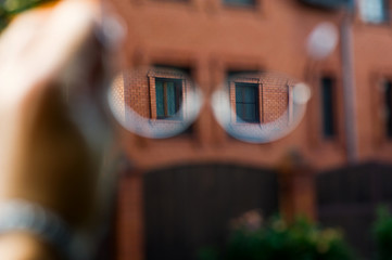 look at a stone house through glasses. Selective sharpness in glasses, the rest of the space is blurry. View of the world through glasses