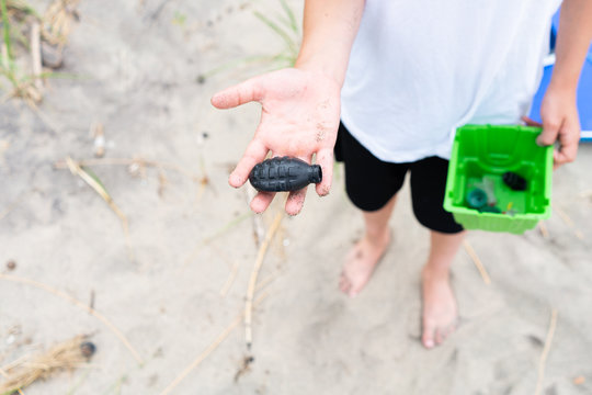 Directly above view of boy holding non biodegradable waste during beach clean up