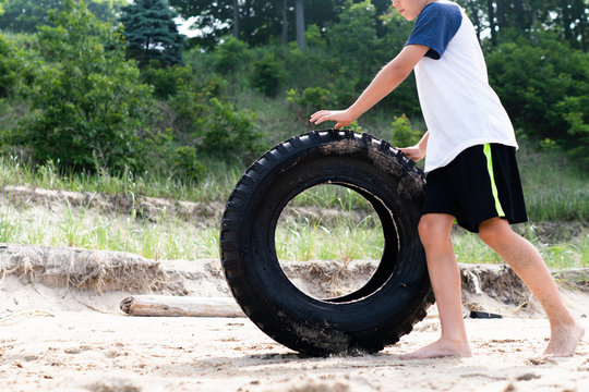 Close up view of child rolling away tire from lake shore