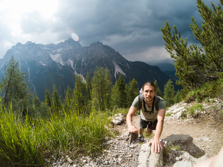 Man on the hill watching wonderful scenery in mountains during summer colorful sunset in Italy Alps. Travel Lifestyle hiking concept summer vacations outdoor.