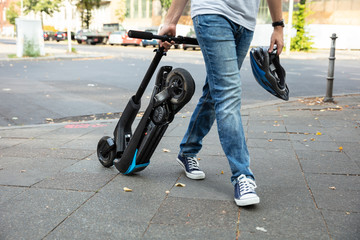 Man Carrying E-Scooter To Work