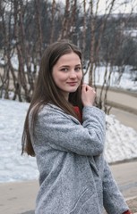 women with red hair in beautiful beige scarf and grey coat posing in a winter forest or park.