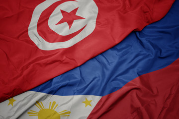 waving colorful flag of philippines and national flag of tunisia.