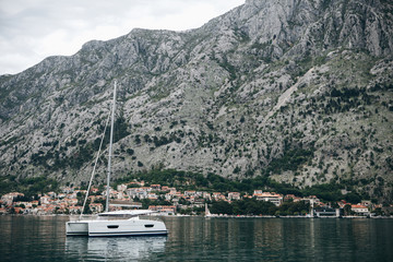 Fototapeta na wymiar Beautiful view of the mountains, coastal city, sea and a sailboat or boat in the foreground. Natural landscape in Montenegro.