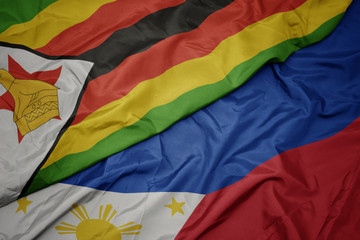 waving colorful flag of philippines and national flag of zimbabwe.